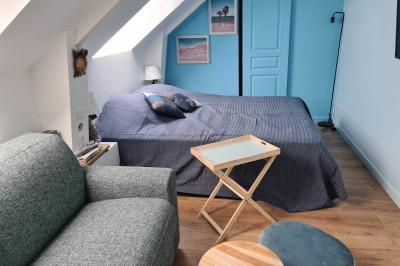 Douche à l'italienne avec carrelage sombre à gauche et lavabo blanc sur meuble en bois à droite.