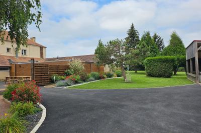 Douche à l'italienne avec carrelage sombre à gauche et lavabo blanc sur meuble en bois à droite.