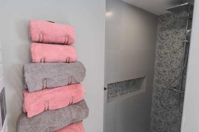 Douche à l'italienne avec carrelage sombre à gauche et lavabo blanc sur meuble en bois à droite.