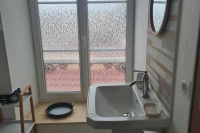 Douche à l'italienne avec carrelage sombre à gauche et lavabo blanc sur meuble en bois à droite.