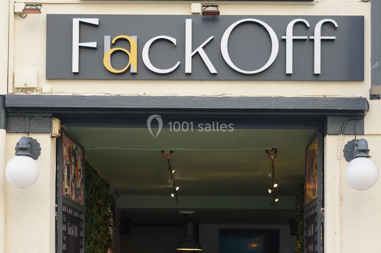 Enseigne noire avec l'inscription ’FackOff’ au-dessus de l'entrée d'un bâtiment éclairé.