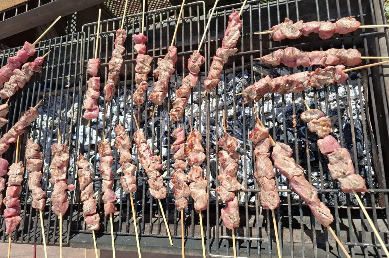 Brochettes de viande en train de griller sur un barbecue à charbon.