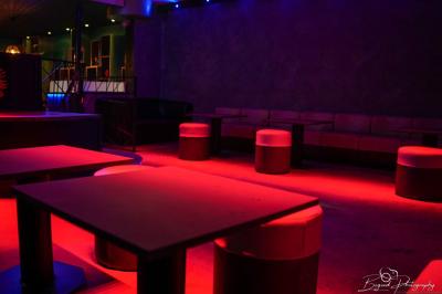 Vue d'une salle de bain avec un lavabo en vasque noire sur un plan en bois et un éclairage mural tamisé.