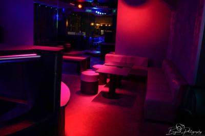 Vue d'une salle de bain avec un lavabo en vasque noire sur un plan en bois et un éclairage mural tamisé.