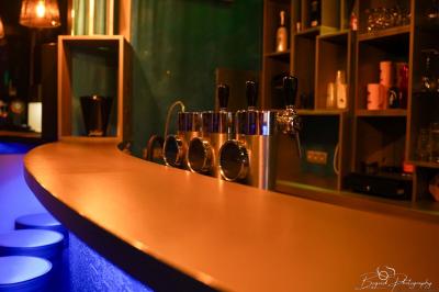 Vue d'une salle de bain avec un lavabo en vasque noire sur un plan en bois et un éclairage mural tamisé.