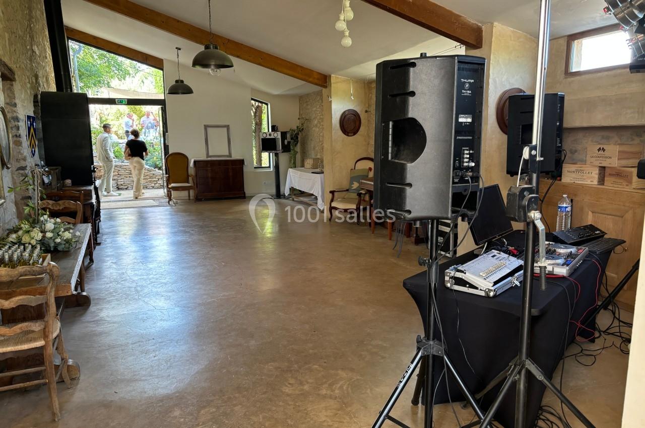 Salle lumineuse avec murs en pierre, équipement audio à droite et vue sur un jardin à travers une grande baie vitrée.