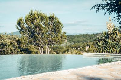 Chambre rustique avec lit double, poutres apparentes, mobilier en bois et salle de bain attenante en arrière-plan.