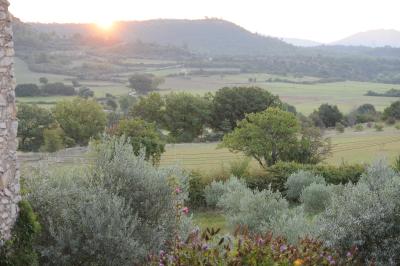 Chambre rustique avec lit double, poutres apparentes, mobilier en bois et salle de bain attenante en arrière-plan.