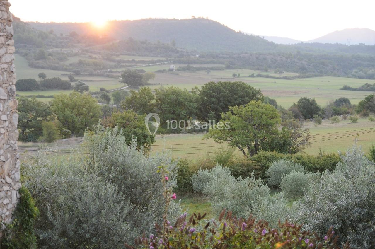 Paysage champêtre au lever du soleil avec des collines, des arbres et des champs verdoyants.