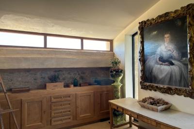 Chambre rustique avec lit double, poutres apparentes, mobilier en bois et salle de bain attenante en arrière-plan.