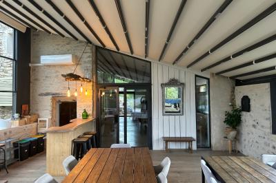 Chambre rustique avec lit double, poutres apparentes, mobilier en bois et salle de bain attenante en arrière-plan.