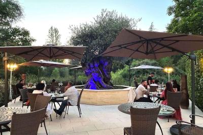 Piscine extérieure entourée de végétation, transats et parasols noirs, avec des rochers décoratifs au premier plan.
