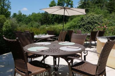 Piscine extérieure entourée de végétation, transats et parasols noirs, avec des rochers décoratifs au premier plan.