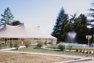 Table élégamment dressée en extérieur avec des fleurs pastel, des bougies et une grande bâtisse en arrière-plan.