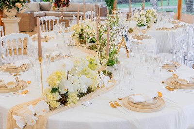 Table élégamment dressée en extérieur avec des fleurs pastel, des bougies et une grande bâtisse en arrière-plan.