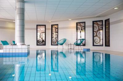 Chambre lumineuse avec lit double, bureau, télévision, machine à café et grande fenêtre offrant une vue extérieure.