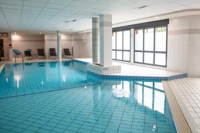 Chambre lumineuse avec lit double, bureau, télévision, machine à café et grande fenêtre offrant une vue extérieure.