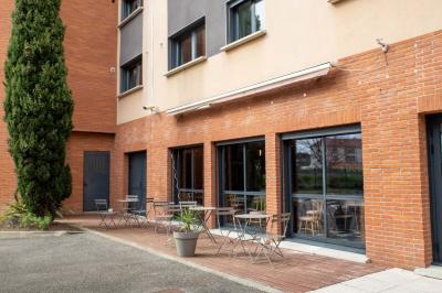 Chambre lumineuse avec lit double, bureau, télévision, machine à café et grande fenêtre offrant une vue extérieure.