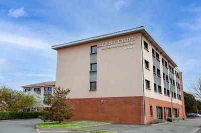 Chambre lumineuse avec lit double, bureau, télévision, machine à café et grande fenêtre offrant une vue extérieure.
