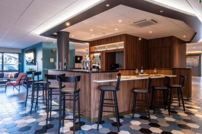 Chambre lumineuse avec lit double, bureau, télévision, machine à café et grande fenêtre offrant une vue extérieure.