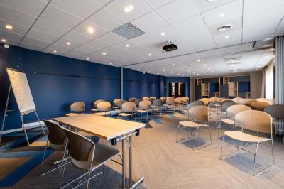 Chambre lumineuse avec lit double, bureau, télévision, machine à café et grande fenêtre offrant une vue extérieure.