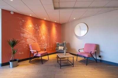 Chambre lumineuse avec lit double, bureau, télévision, machine à café et grande fenêtre offrant une vue extérieure.