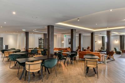 Chambre d'hôtel lumineuse avec un grand lit, des lampes de chevet, un bureau, une télévision et une fenêtre avec rideaux.