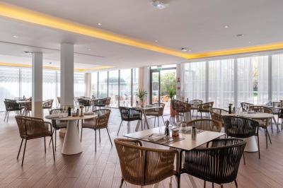 Chambre d'hôtel lumineuse avec un grand lit, des lampes de chevet, un bureau, une télévision et une fenêtre avec rideaux.