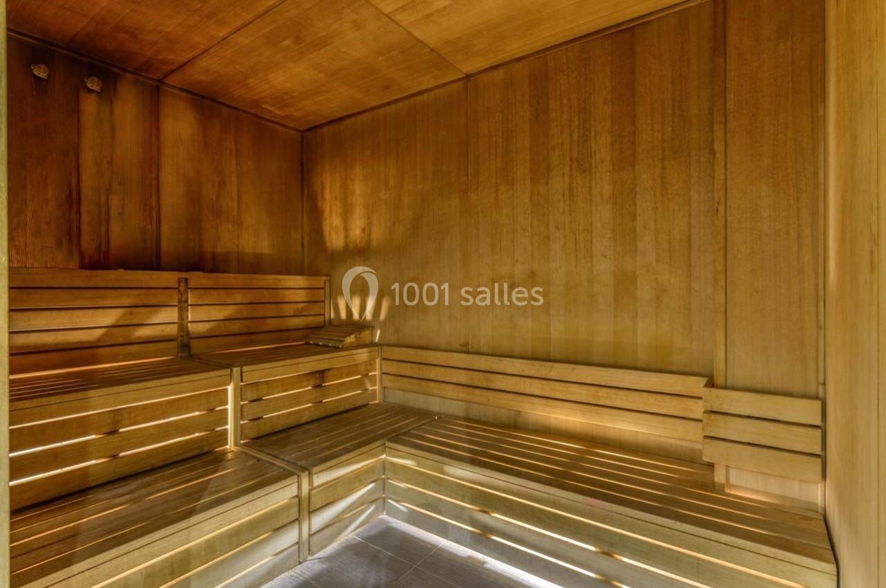Intérieur d'un sauna en bois avec bancs disposés en gradins et éclairage tamisé.