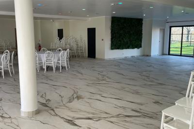 Comptoir en bois éclairé par des suspensions, avec machines à café et sol en marbre dans un espace moderne.