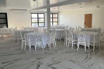 Comptoir en bois éclairé par des suspensions, avec machines à café et sol en marbre dans un espace moderne.