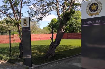 Comptoir en bois éclairé par des suspensions, avec machines à café et sol en marbre dans un espace moderne.