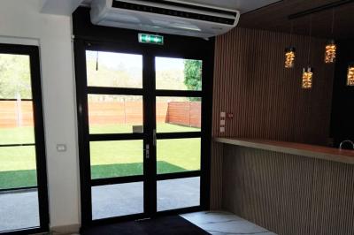 Comptoir en bois éclairé par des suspensions, avec machines à café et sol en marbre dans un espace moderne.