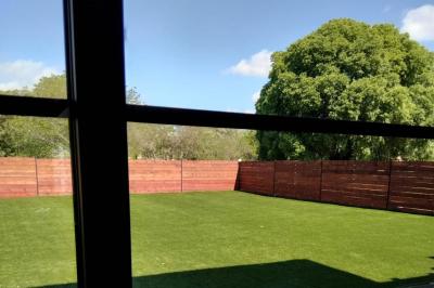 Comptoir en bois éclairé par des suspensions, avec machines à café et sol en marbre dans un espace moderne.