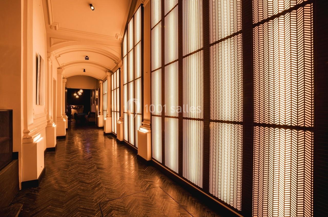 Couloir avec parquet en bois sombre, éclairé par des panneaux lumineux aux motifs géométriques.