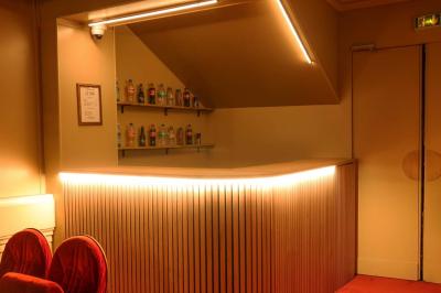 Salle avec moquette rouge, table en bois clair, chaises rouges et miroir éclairé par des ampoules.