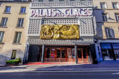 Salle avec moquette rouge, table en bois clair, chaises rouges et miroir éclairé par des ampoules.
