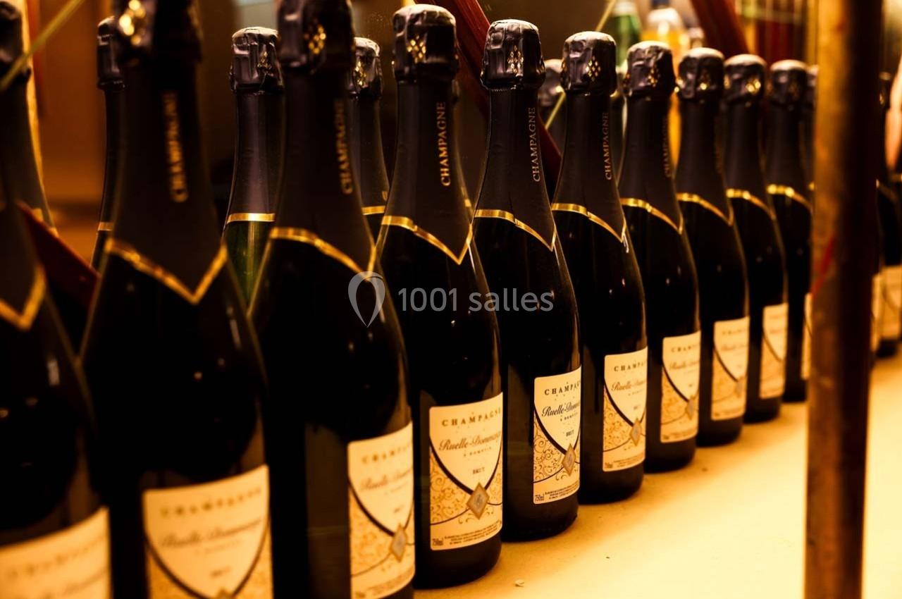 Bouteilles de champagne alignées sur une étagère, éclairées par une lumière chaude.