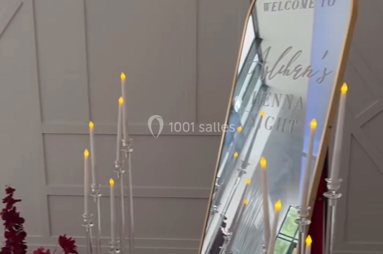 Panneau miroir décoratif avec un message gravé, entouré de bougies LED et de fleurs rouges.