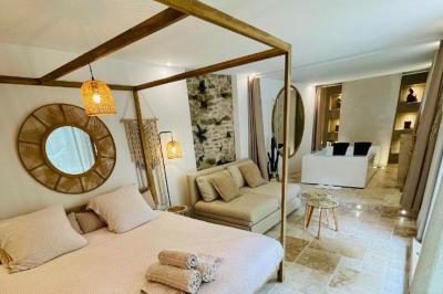 Chambre lumineuse avec jacuzzi intégré, lit double, murs en pierre blanche et décoration élégante.