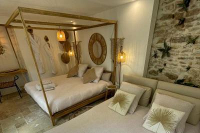 Chambre lumineuse avec jacuzzi intégré, lit double, murs en pierre blanche et décoration élégante.