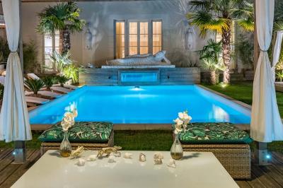 Chambre lumineuse avec jacuzzi intégré, lit double, murs en pierre blanche et décoration élégante.