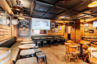 Salle de bar avec des murs en bois, des tables et chaises alignées, et une grande inscription ’French Flair’ sur le mur.