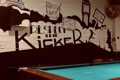 Salle de bar avec des murs en bois, des tables et chaises alignées, et une grande inscription ’French Flair’ sur le mur.