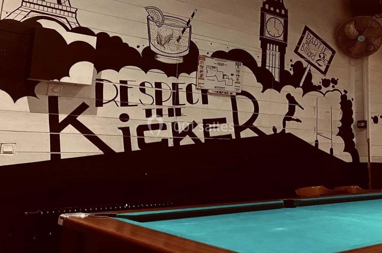 Mur décoré avec des illustrations de monuments, un cocktail et une table de billard au premier plan.