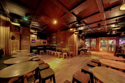 Salle de bar avec des murs en bois, des tables et chaises alignées, et une grande inscription ’French Flair’ sur le mur.