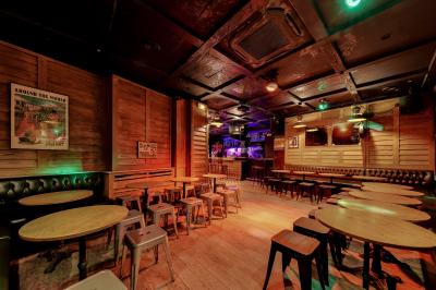 Salle de bar avec des murs en bois, des tables et chaises alignées, et une grande inscription ’French Flair’ sur le mur.