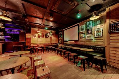 Salle de bar avec des murs en bois, des tables et chaises alignées, et une grande inscription ’French Flair’ sur le mur.
