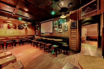 Salle de bar avec des murs en bois, des tables et chaises alignées, et une grande inscription ’French Flair’ sur le mur.