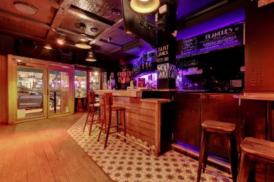 Salle de bar avec des murs en bois, des tables et chaises alignées, et une grande inscription ’French Flair’ sur le mur.